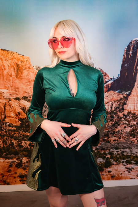 Blonde woman in a green velvet dress and heart sunglasses