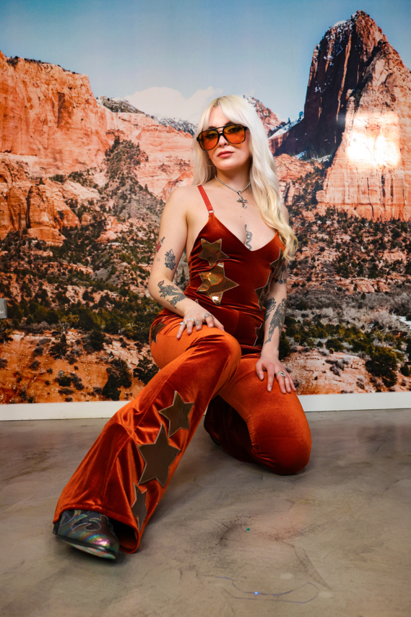 blonde woman in a burnt orange jumpsuit with gold stars