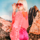 blonde woman in a neon peach top and pink shorts