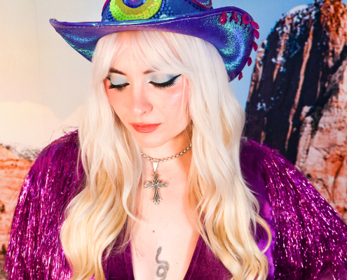 Blonde woman in a purple jacket and blue western hat